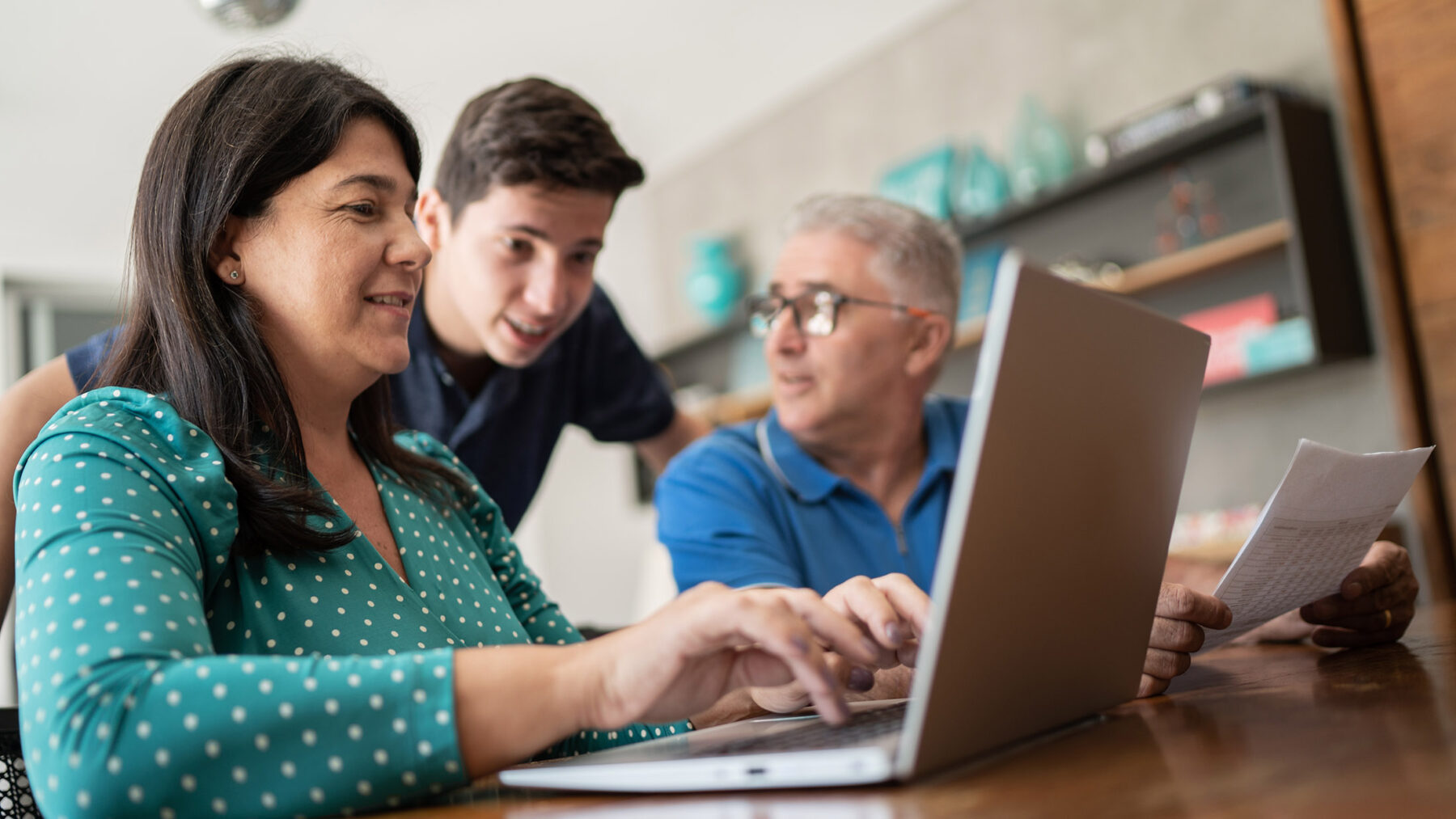 Parents working on laptop while teenage boy looks over their shoulders