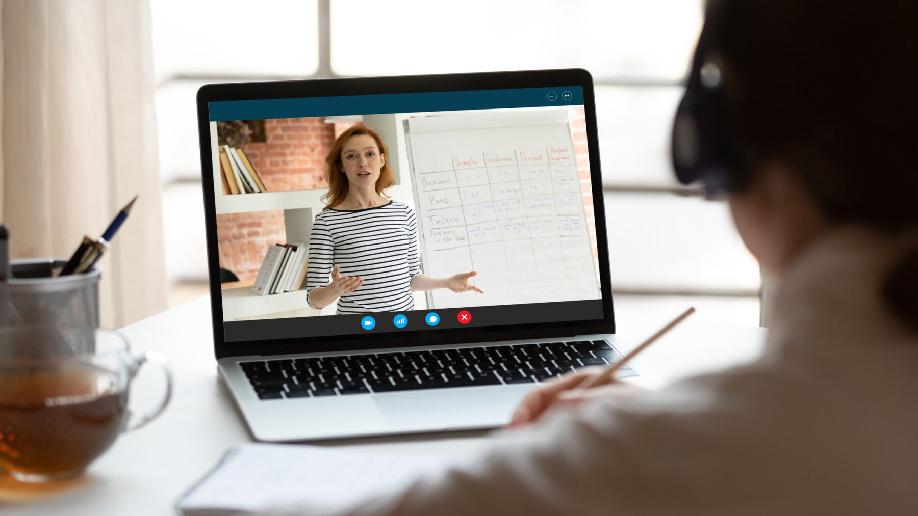 Rear view close up woman wearing headphones watching webinar on a laptop